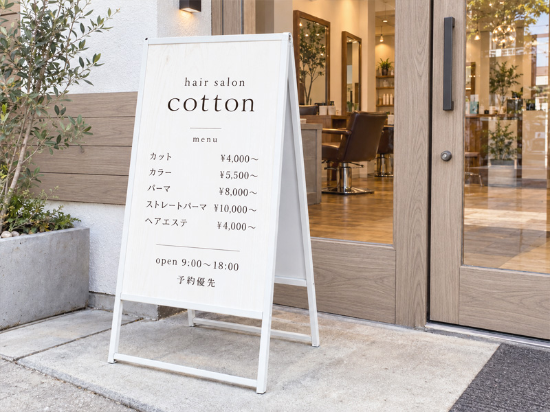 白と木目を基調としたサロン入口に置かれたスタンド看板のデザインイメージ